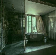 an old fashioned bathtub sits in front of a window with sheer curtains on it