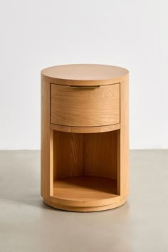 a round wooden table with an open drawer on the bottom and one shelf below it