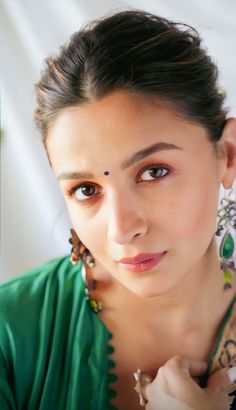 a woman in a green shirt is posing for the camera with her hand on her neck