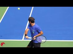 a young man holding a tennis racquet on top of a tennis court with a ball in the air