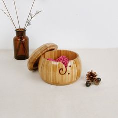 an elephant shaped wooden bowl next to a small pine cone and vase with flowers in it