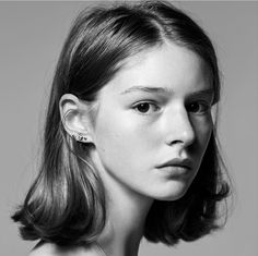 a young woman with short hair and piercings on her ears is looking at the camera