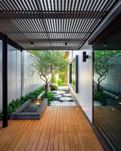 an outdoor area with wooden flooring and plants on the walls, along with a water feature