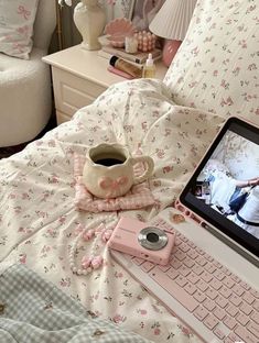 an open laptop computer sitting on top of a bed next to a cup of coffee