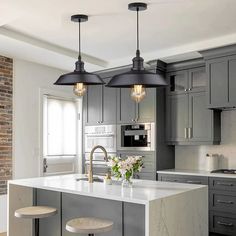 a kitchen island with two stools next to it and lights hanging from the ceiling