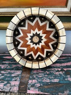 a wooden plate sitting on top of a table next to a painting and a wall