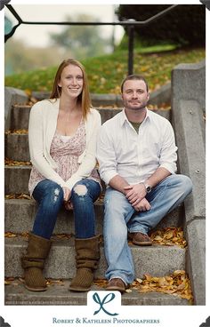 a man and woman sitting on the steps in front of some stairs with leaves all over them