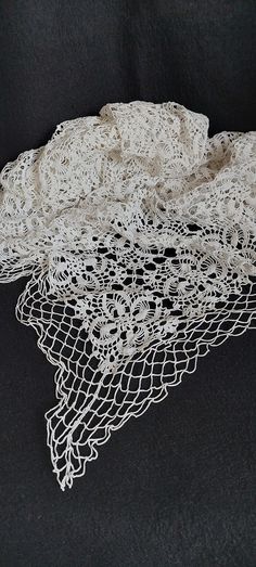 three pieces of white crocheted fabric on a black tablecloth covered with lace