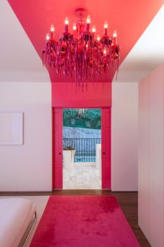 a pink room with a chandelier hanging from the ceiling and a red rug on the floor