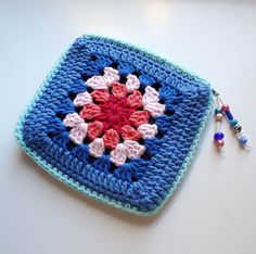 a crocheted square with a beaded keychain hanging from the side