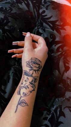 a woman's arm with tattoos on it and a rose tattooed on the wrist