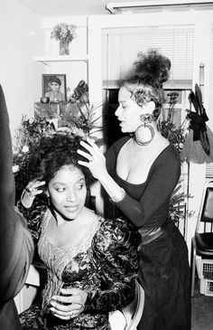 black and white photograph of woman getting her hair styled by another woman in the background