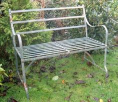 an old metal bench sitting in the grass