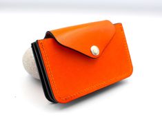 Handmade using traditional leather artisan techniques and beautiful vegetable tanned leather from Italy in a fun vibrant orange colour.  The internal pockets are made from slim and hard wearing latigo leather in a smart contrasting navy blue.  Going out out is all about the minimal now and this clever little purse can carry multiple cards and banknotes and still fit in the smallest of handbags and clutch bags.   It has a clever concertina design so it can carry many cards without being bulky.   Personalised for free!  Just add the name or initials that you would like  (up to 8 characters).  This will be positioned on the front, bottom right corner.   Please note that returns for personalised items cannot be accepted.  - handmade - personalised for free - can fit cards comfortably plus bank Orange Card Holder With Card Slots For Everyday Use, Orange Rectangular Card Holder With Slots, Orange Rectangular Card Holder With Card Slots, Orange Leather Wallet As Gift, Orange Leather Wallet For Daily Use, Orange Leather Bifold Wallet, Orange Wallet With Card Slots For Daily Use, Orange Leather Wallets With Interior Card Slots, Orange Leather Wallet With Card Slots