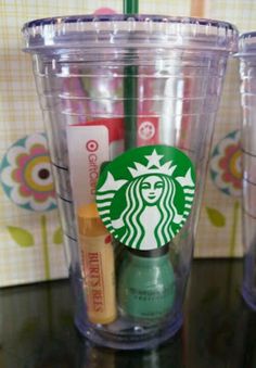 the starbucks cup is next to two cups with pens and markers on them, one has a green straw sticking out of it