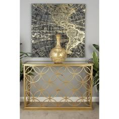 a gold console table with a painting on the wall behind it and a plant in front of it