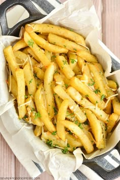 french fries with parmesan cheese and herbs in a serving dish on a wooden table