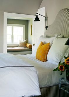 a bedroom with white bedding and yellow pillows