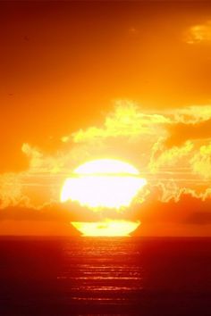 the sun is setting over the ocean with clouds