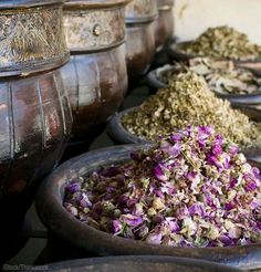 many bowls filled with different types of flowers and spices on top of each other in them