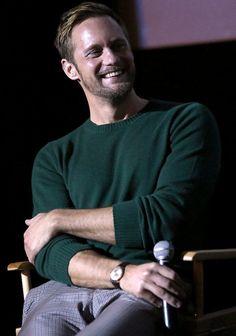 a man sitting in a chair with his arms crossed and looking at the camera while smiling