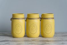 three yellow mason jars sitting on top of a wooden table