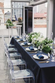 the table is set with blue and white plates, silverware, and greenery