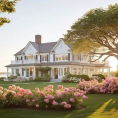 a large white house surrounded by flowers and trees