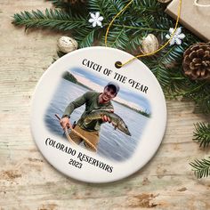 a christmas ornament with a photo of a man holding a fish on it