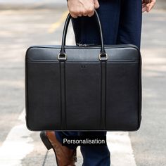 "Slim Black Leather Briefcases, carefully handmade by the finest craftsmen of the city of Mumbai, India. An ideal choice for daily commute and weekend travel. EXTERIOR : The Exterior is made from 100% Genuine Pebble Grain Leather, designed to be unaffected by wear and tear of everyday use. The Top handles are made from 100% Genuine Leather. The Leather used for the Top Handles, requires it to be stiff. Texture of this Leather is smooth. INTERIOR : The interior is made from OEKO-TEX® certified Po Minimalist Business Briefcase, Minimalist Business Bag With Luggage Sleeve, Black Minimalist Laptop Bag For Office, Minimalist Black Laptop Bag With Sleeve, Minimalist Black Business Laptop Bag, Minimalist Black Laptop Bag With Laptop Sleeve, Minimalist Black Laptop Bag For Business, Minimalist Leather Laptop Bag For Business, Modern Briefcase For Daily Use