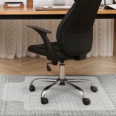 an office chair sitting on top of a rug in front of a desk with a computer