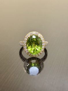 DeKara Designs Collection Our latest design! An elegant and lustrous Peridot Halo Diamond Engagement Ring. Metal- 18K Yellow Gold, .750. Stones- Oval Natural Peridot 11.6 MM x 9.4 MM 4.16 Carats, 44 Round Diamonds F-G Color VS1-VS2 Clarity 0.46 Carats. Latest of my creations! A Beautiful Peridot Diamond Halo Engagement Ring Made in 18K Yellow Gold. There is a beautiful genuine green peridot in the center of the ring that is professionally set in between four double prongs. The peridot is a beaut Luxury Green Diamond Ring With Halo Design, Luxury Green Halo Ring With Center Stone, Luxury Green Gemstone Halo Ring, Elegant Peridot Diamond Ring With Center Stone, Oval Tsavorite Ring With Gemstone Accents, Luxury Green Halo Diamond Ring, Luxury Oval Peridot Rings, Green Luxury Halo Diamond Ring, Luxury Yellow Gold Peridot Rings