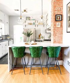 three green chairs sit at the center of a kitchen island in front of a brick wall