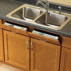 two stainless steel sinks in a kitchen with granite counter tops and wooden cabinets, under a faucet