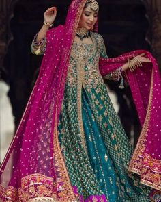 a woman in a blue and pink bridal outfit with her hands on her hip