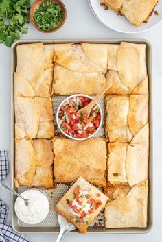 pita bread cut into squares with salsa and sour cream in the middle on a tray