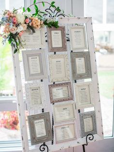 an old window is decorated with framed photos and flowers on the table for guests to sit at