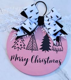 a pink ornament with black and white bows on it that says merry christmas