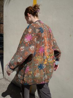 a woman is walking down the street in an oversize jacket with flowers on it