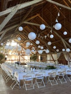 the tables are set up for an event with white paper lanterns hanging from the ceiling