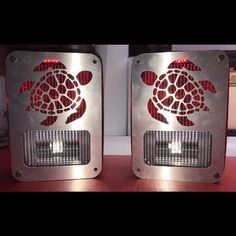 two speakers are sitting on a table with a turtle in the center and red lights behind them