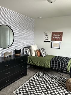 a bedroom with a bed, dresser and mirror on the wall next to a black dresser