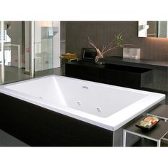 a large white bath tub sitting in a bathroom next to a black counter and mirror