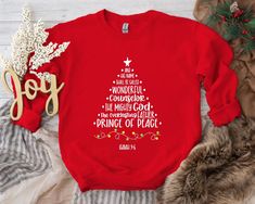 "Rejoice in the true meaning of Christmas with our \"And His Name Shall Be Called Christmas Tree Sweatshirt.\" This unique tee beautifully arranges the words \"And His Name Shall Be Called Wonderful Counselor The Mighty God Everlasting Father Prince Of Peace\" to form a majestic Christmas tree, complete with a shining star at the top, honoring the many names of Jesus. Inspired Design: Our Sweatshirt creatively arranges the names of Jesus to form a stunning Christmas tree, offering a beautiful an Chemical Design, Teacher Sweater, Wonderful Counselor, Jesus Sweatshirts, Unique Sweatshirt, Christmas Tree Shirt, True Meaning Of Christmas, Xmas Shirts, Tree Shirt