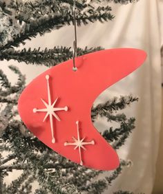 a red ornament hanging from a tree with white snowflakes on it