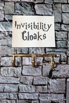 a sign hanging on the side of a brick wall that says, invisibity cloaks