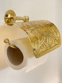 a gold toilet paper holder is hanging on the wall