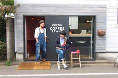 two people sitting on stools in front of a coffee shop with the door open