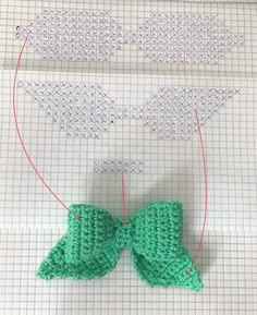 a crocheted green bow on top of a piece of paper