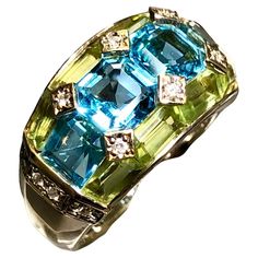 A beautifully made ring done in 18K yellow gold that has been set with 3.35cttw in blue topaz, 2.46cttw, 2.46cttw in green peridot and .09cttw in H-I color Si1-2 clarity diamonds… such a color combination! All weights are stamped inside of the shank. Dimensions/Weight: Ring measures .45” top to bottom and weighs 10.8g. Size 6 (sizable). Condition: All stones are secure and in perfectly wearable condition. R-TYE Luxury Fusion Multi-stone Rings, Luxury Multicolor Round Topaz Ring, Multi Gemstone Ring Jtv, Green Peridot, Color Ring, Gem Stone, Dear Santa, Cluster Ring, Cocktail Rings